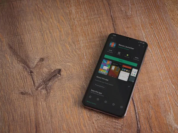 Lod, Israel - 8 Temmuz 2020: Nova Launcher uygulaması oyun mağazası sayfası ahşap arka planda siyah bir cep telefonu ekranında. Üst görünüm düzlüğü kopyalama alanı ile yatıyordu.