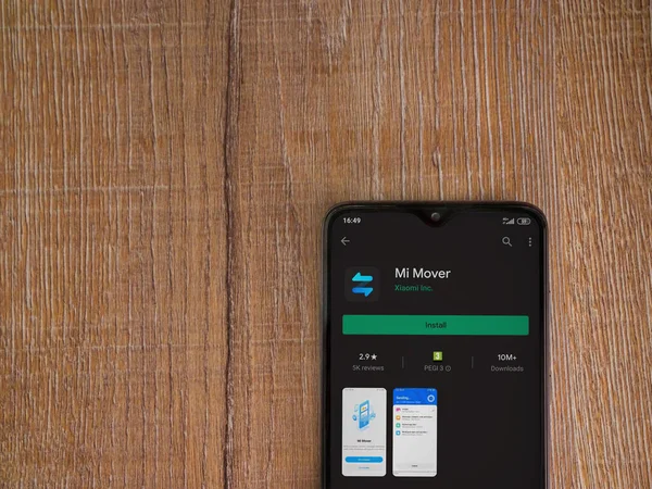 Lod, Israel - 8 Temmuz 2020: Mi Mover uygulama oyun mağazası sayfası ahşap arka planda siyah bir cep telefonunun ekranında. Üst görünüm düzlüğü kopyalama alanı ile yatıyordu.