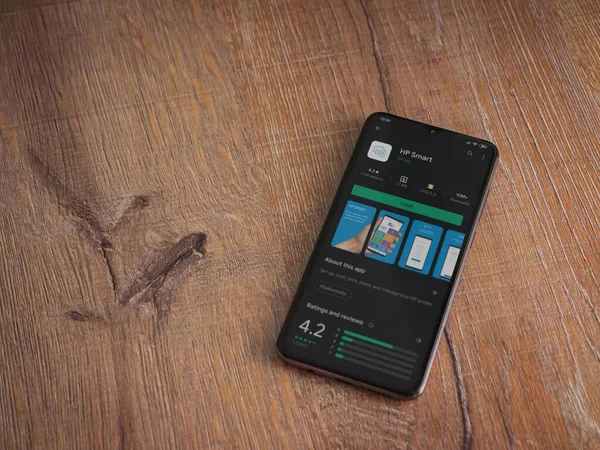 Lod, Israel - 8 Temmuz 2020: HP Smart uygulama oyun mağazası sayfası ahşap arka planda siyah bir cep telefonunun ekranında. Üst görünüm düzlüğü kopyalama alanı ile yatıyordu.