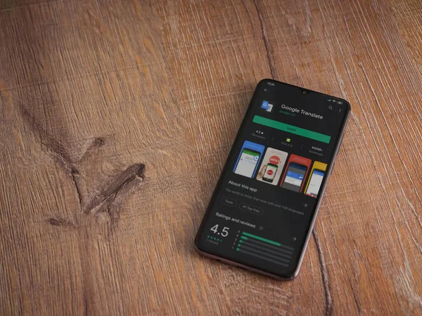 Lod, Israel - 8 Temmuz 2020: Google Translate uygulama oyun mağazası sayfası ahşap arka planda siyah bir cep telefonunun ekranında. Üst görünüm düzlüğü kopyalama alanı ile yatıyordu.