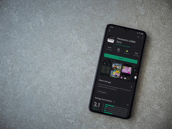 Lod, Israel - 8 Temmuz 2020: Panasonic LUMIX Sync uygulama oyun mağazası sayfası seramik taş zemin üzerinde siyah bir cep telefonu görüntüsü. Üst görünüm düzlüğü kopyalama alanı ile yatıyordu.
