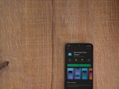 Lod, Israel - 8 Temmuz 2020: Ben Gurion Havalimanı uygulama oyun mağazası sayfası ahşap arka planda siyah bir cep telefonunun ekranında. Üst görünüm düzlüğü kopyalama alanı ile yatıyordu.
