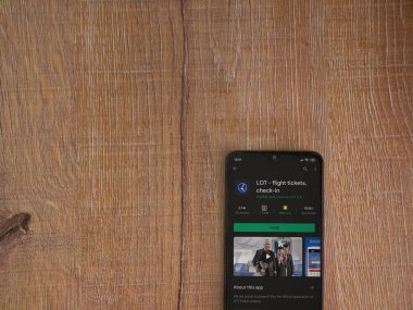 Lod, Israel - 8 Temmuz 2020: LOT uygulama oyun mağazası sayfası ahşap arka planda siyah bir cep telefonunun ekranında. Üst görünüm düzlüğü kopyalama alanı ile yatıyordu.