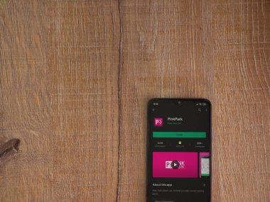 Lod, Israel - 8 Temmuz 2020: Pembe Park uygulama oyun mağazası sayfası ahşap arka planda siyah bir cep telefonunun ekranında. Üst görünüm düzlüğü kopyalama alanı ile yatıyordu.
