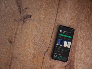 Lod, Israel - 8 Temmuz 2020: İsrail Demiryolları uygulama oyun mağazası sayfası ahşap arka planda siyah bir cep telefonunun ekranında. Üst görünüm düzlüğü kopyalama alanı ile yatıyordu.