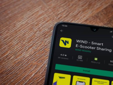 Lod, Israel - 8 Temmuz 2020: Rüzgâr uygulaması oyun mağazası sayfası ahşap arka planda siyah bir cep telefonunun ekranında. Üst görünüm düzlüğü kopyalama alanı ile yatıyordu.