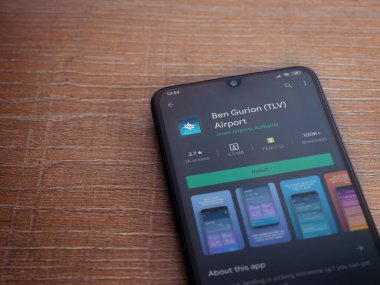 Lod, Israel - 8 Temmuz 2020: Ben Gurion Havalimanı uygulama oyun mağazası sayfası ahşap arka planda siyah bir cep telefonunun ekranında. Üst görünüm düzlüğü kopyalama alanı ile yatıyordu.