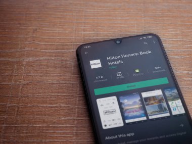 Lod, Israel - 8 Temmuz 2020: Hilton Honors uygulama oyun mağazası sayfası ahşap arka planda siyah bir cep telefonunun ekranında. Üst görünüm düzlüğü kopyalama alanı ile yatıyordu.