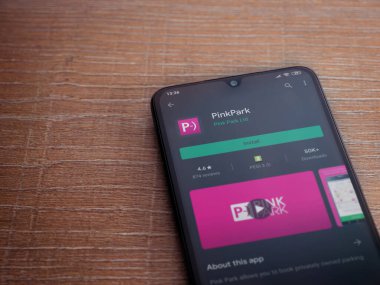 Lod, Israel - 8 Temmuz 2020: Pembe Park uygulama oyun mağazası sayfası ahşap arka planda siyah bir cep telefonunun ekranında. Üst görünüm düzlüğü kopyalama alanı ile yatıyordu.