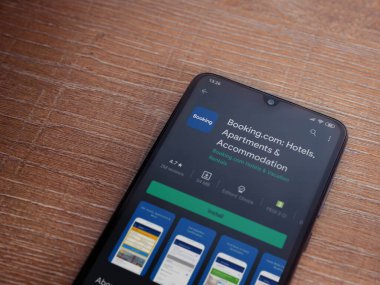 Lod, Israel - 8 Temmuz 2020: Booking.com uygulama oyun mağazası sayfası ahşap arka planda siyah bir cep telefonu görüntüsü. Üst görünüm düzlüğü kopyalama alanı ile yatıyordu.