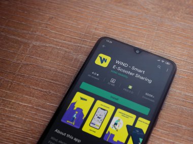 Lod, Israel - 8 Temmuz 2020: Rüzgâr uygulaması oyun mağazası sayfası ahşap arka planda siyah bir cep telefonunun ekranında. Üst görünüm düzlüğü kopyalama alanı ile yatıyordu.