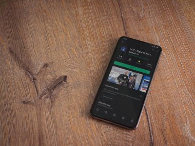 Lod, Israel - 8 Temmuz 2020: LOT uygulama oyun mağazası sayfası ahşap arka planda siyah bir cep telefonunun ekranında. Üst görünüm düzlüğü kopyalama alanı ile yatıyordu.