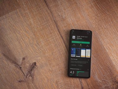 Lod, Israel - 8 Temmuz 2020: İsrail Demiryolları uygulama oyun mağazası sayfası ahşap arka planda siyah bir cep telefonunun ekranında. Üst görünüm düzlüğü kopyalama alanı ile yatıyordu.