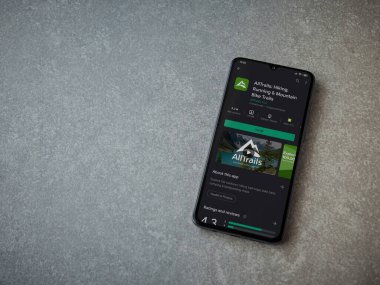 Lod, Israel - 8 Temmuz 2020: AllTrails uygulama oyun mağazası sayfası seramik taş zemin üzerinde siyah bir cep telefonu görüntüsü. Üst görünüm düzlüğü kopyalama alanı ile yatıyordu.