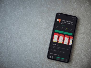 Lod, Israel - 8 Temmuz 2020: Yango Ride uygulaması oyun mağazası sayfası seramik taş zemin üzerinde siyah bir cep telefonu görüntüsü. Üst görünüm düzlüğü kopyalama alanı ile yatıyordu.