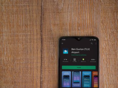 Lod, Israel - 8 Temmuz 2020: Ben Gurion Havalimanı uygulama oyun mağazası sayfası ahşap arka planda siyah bir cep telefonunun ekranında. Üst görünüm düzlüğü kopyalama alanı ile yatıyordu.