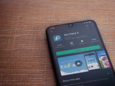 Lod, Israel - 8 Temmuz 2020: Ibis Paint X uygulama oyun mağazası sayfası, ahşap arka planda siyah bir cep telefonu görüntüsü. Üst görünüm düzlüğü kopyalama alanı ile yatıyordu.