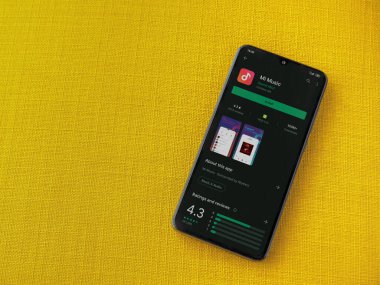 Lod, Israel - 8 Temmuz 2020: Mi Music uygulama oyun mağazası sayfası sarı kumaş arka planda siyah bir cep telefonunun ekranında. Üst görünüm düzlüğü kopyalama alanı ile yatıyordu.