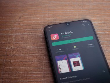 Lod, Israel - 8 Temmuz 2020: Mi Music uygulama oyun mağazası sayfası ahşap arka planda siyah bir cep telefonunun ekranında. Üst görünüm düzlüğü kopyalama alanı ile yatıyordu.