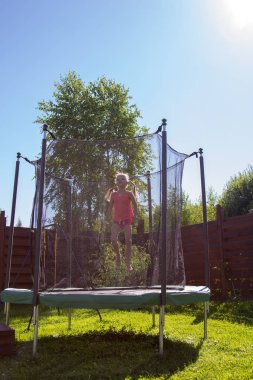 koruyucu ağ arkasında bir trambolin üzerinde atlama kız