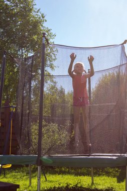 koruyucu ağ arkasında bir trambolin üzerinde atlama kız