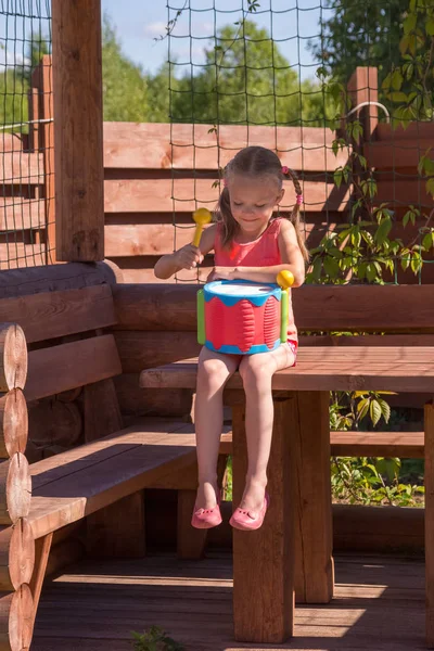 Meisje spelen met een drum in houten Arbor — Stockfoto