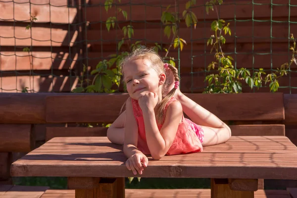 Meisje liggend op de tafel in houten Arbor — Stockfoto