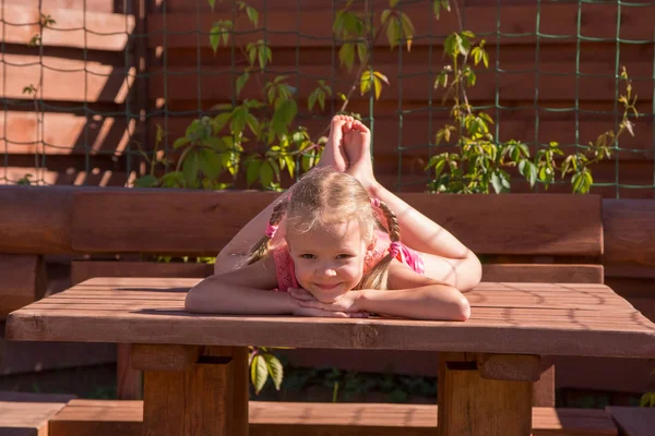 Menina deitada na mesa no eixo de madeira — Fotografia de Stock