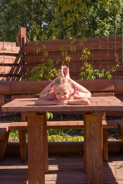 Meisje liggend op de tafel in houten Arbor — Stockfoto