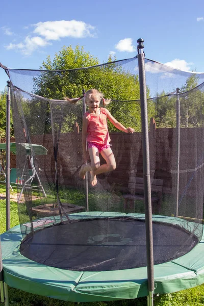 Meisje springt op een trampoline achter beschermend net — Stockfoto