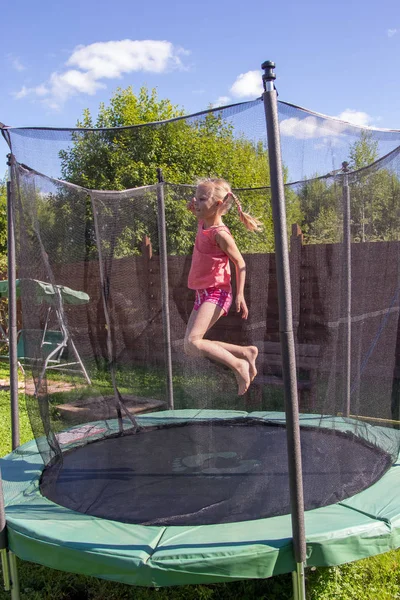 Meisje springt op een trampoline achter beschermend net — Stockfoto
