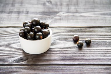 Tahta arka plandaki kasede taze kuşüzümü var.