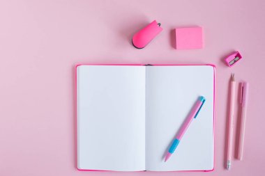 Pembe arka planda okul defteri ve kırtasiye malzemesi. Okul konseptine dönelim.