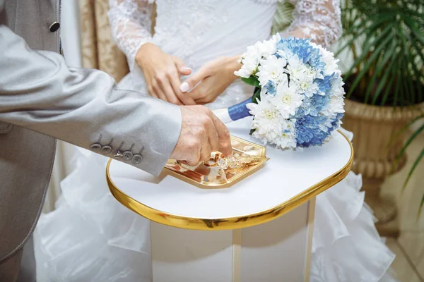 Düğün töreni. Bir damat gelininin parmağına bir alyans takmak üzere.