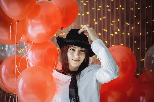 Kırmızı baloons ve havai fişek arasında kutlama sırasında stanning kız. Şapkalı bir kız..