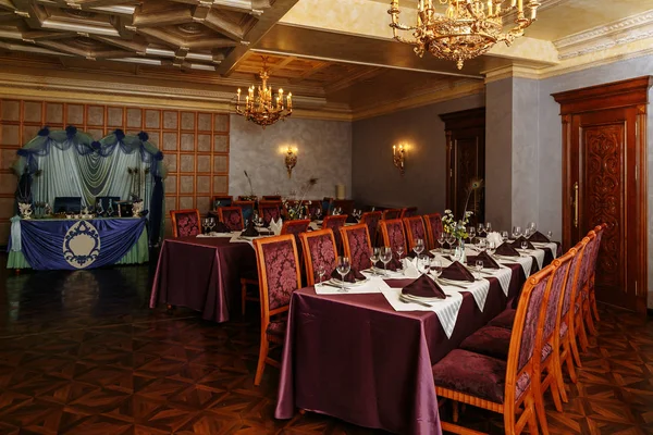 Bir restoranın rahat iç. Yemek odasının muhteşem manzarası. Tatil için her şey hazır. Kırmızı ahşap zemin, kırmızı sandalyeler ve bordo masa örtüleri. Lüks avizeler ile altın tavan. 