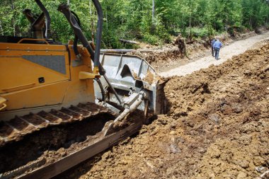 Bir yol inşaatı. Buldozer işte. Bir ormanı yok etmek. Kırık ve düşmüş ağaçlar. arka planda mavi bir gökyüzü ile. 