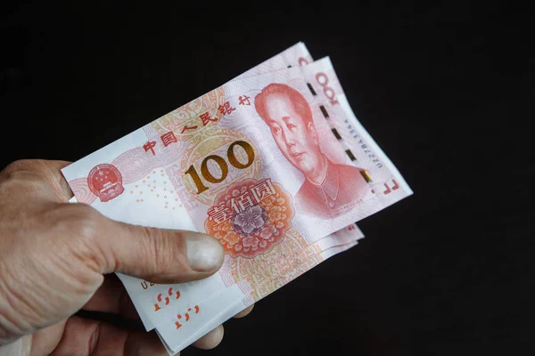Siyah arka plan. 100 yuan banknot. Yüz Cny. Çin para birimi. Bir paket banknot. Elinde yuan yığını.