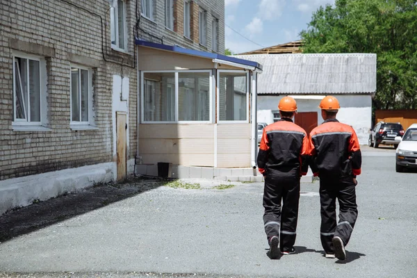 Twee Mannen Lopen Werkende Kleren Het Dragen Van Oranje Helmen Stockfoto