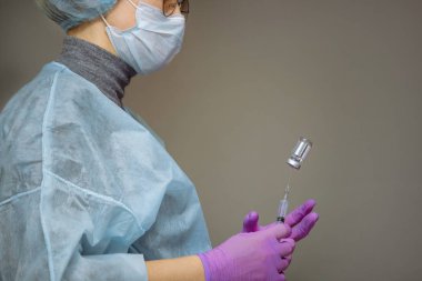 Şırınga ve ilaç ile doktor, gri üzerinde izole. Soğuk ilaç ve grip virüsü seti. Elinde bir ilaç ile şırınga, çekim.