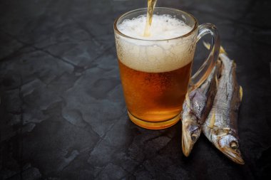 Bira ve kurutulmuş balık. Siyah arka planda kurutulmuş balık ile Cam bira. Bira arka planı. Kopyalama alanı