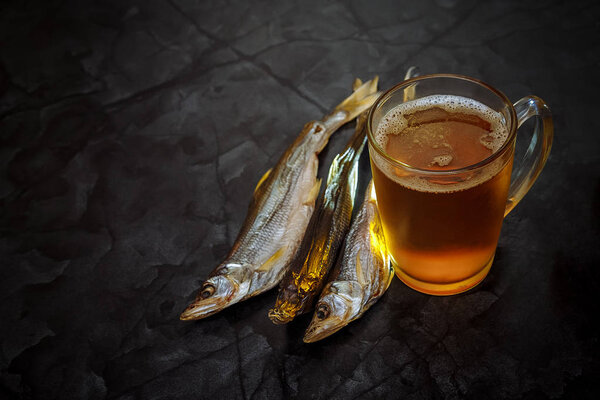 Beer and dried fish. Glass beer with dried fish on black background. Beer background. Copy space