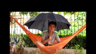 Yağmur yağdığında hamak şemsiyesi altındaki çocuklar.