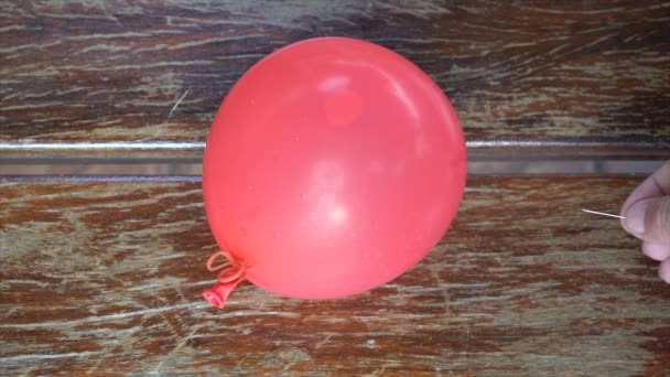 带水的红色气球在木桌上被针头打破 — 图库视频影像