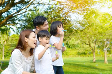 Güzel Asyalı aile kabarcıklar parkta üfleme