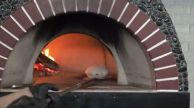Tanınmayan erkek Baker ekmek bir odun yanan soba üzerinde kabartma için döner. Şef Bakes gözleme Pide taş fırında.