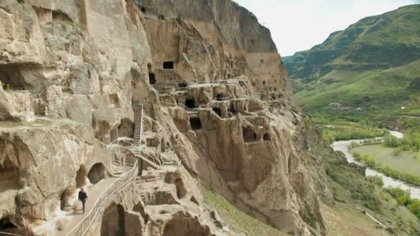 Een toerist onderzoekt de bezienswaardigheden van Georgia Vardzia grot klooster. — Stockvideo