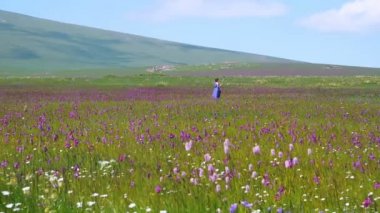 Fotoğrafta selfie sopayla purle çiçekli çayır üzerinde oldukça beyaz kız. Mutlu bir güzel genç kadın uzun mor içinde yapmak selfie doğa arka plan üzerinde elbise. Açık havada güzel bir kadın. Yaz