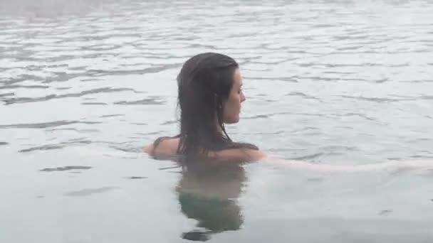 Γεωθερμικά σπα. Γυναίκα χαλαρώνοντας στην πισίνα ζεστό άνοιξη. Κορίτσι απολαμβάνοντας κολύμβησης opendoor λεκάνη με το ζεστό μεταλλικό νερό 30fps — Αρχείο Βίντεο