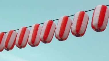 Kırmızı-beyaz Japon lambaları Chochin kağıt mavi bulutlu gökyüzü arka plan üzerinde asılı